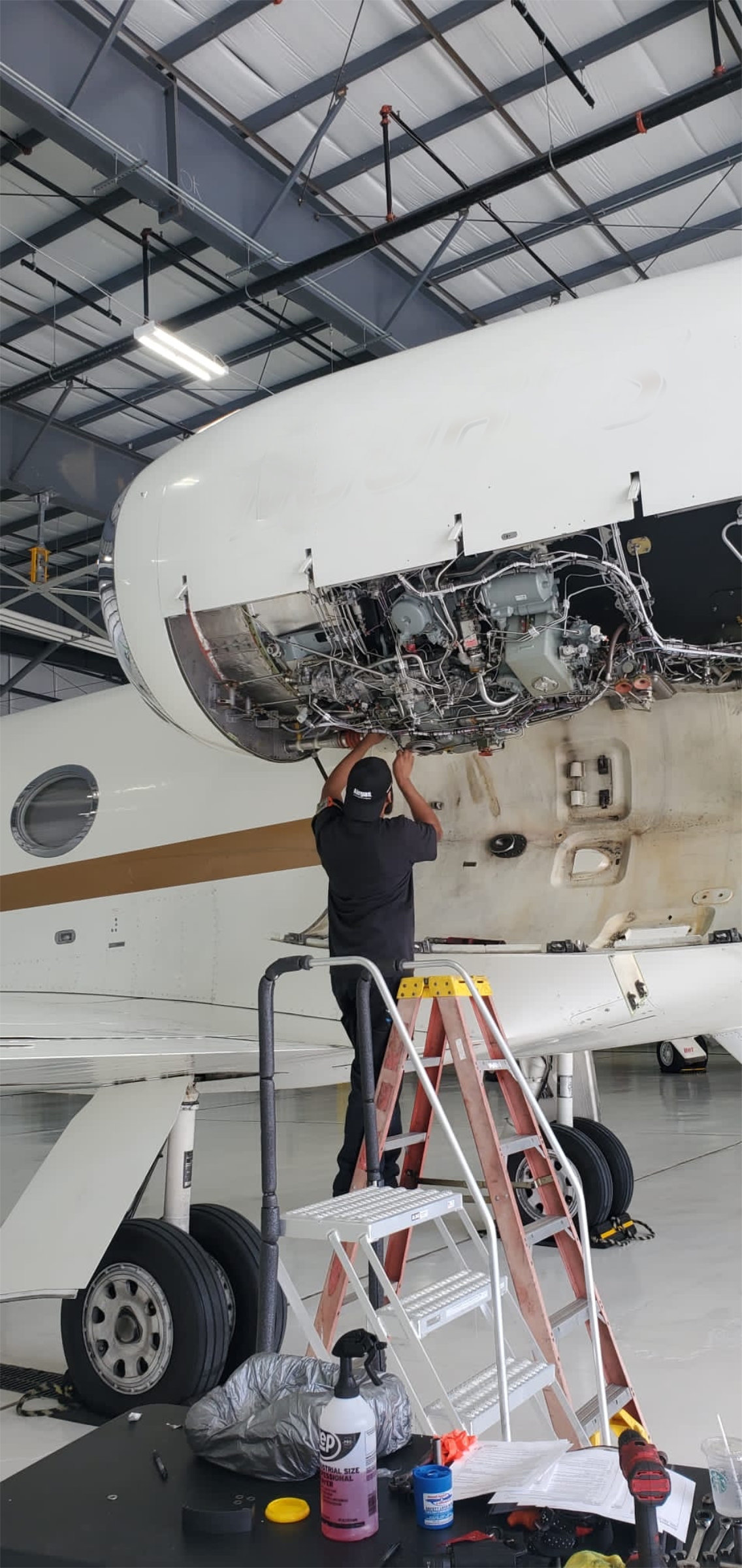 Heavy Metal Air mechanic working under a business jet on a maintenance stand